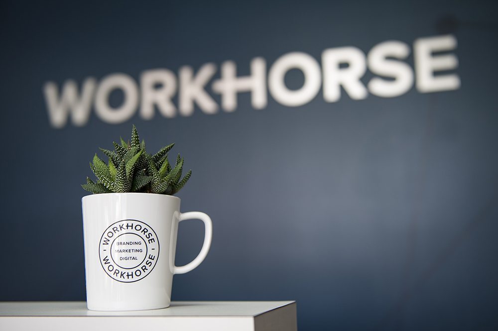 Artistic shot of a cup on a desk at the Workhorse Marketing new office, with the Workhorse logo in the background