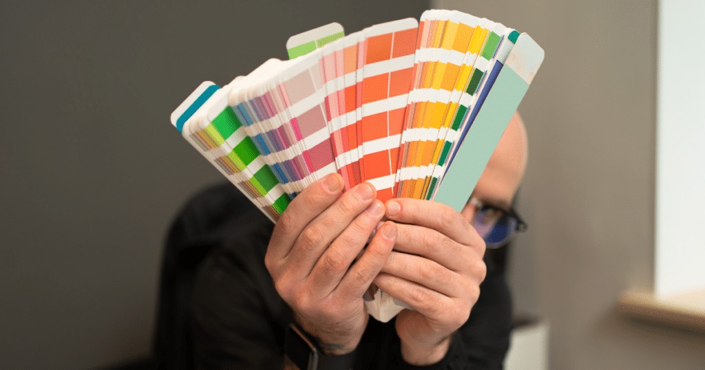 A close-up of a Pantone color bridge guide being held by a designer with the deck opened up in the shape of a fan.